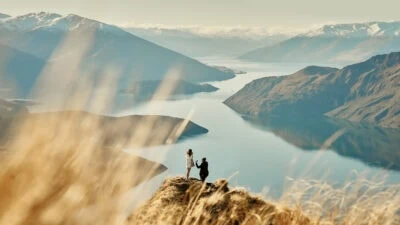 Kyoto Tokyo Japan Elopement Wedding Photographer, Planner & Videographer | Two people standing on top of a mountain overlooking lake wanaka.