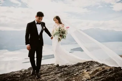 Kyoto Tokyo Japan Elopement Wedding Photographer, Planner & Videographer | A bride and groom standing on top of a mountain overlooking lake wanaka.