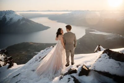 Kyoto Tokyo Japan Elopement Wedding Photographer, Planner & Videographer |      Ayaka Morita captures a breathtaking scene of a bride and groom standing on top of a mountain, overlooking Lake Wanaka. This stunning photograph showcases her talent and would make a valuable addition to her