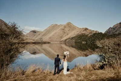 Kyoto Tokyo Japan Elopement Wedding Photographer, Planner & Videographer | Ayaka Morita's portfolio showcases a beautiful image of a bride and groom standing in front of a lake in New Zealand.
