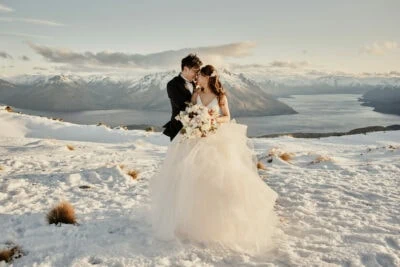 Kyoto Tokyo Japan Elopement Wedding Photographer, Planner & Videographer | Ayaka Morita's portfolio features a stunning image of a bride and groom standing on top of a snow covered mountain in Queenstown, New Zealand.