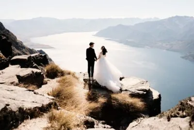 Kyoto Tokyo Japan Elopement Wedding Photographer, Planner & Videographer | Ayaka Morita captures a stunning portfolio shot of a bride and groom standing on top of a cliff overlooking lake Wanaka.