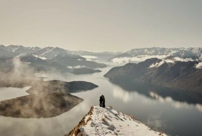 Kyoto Tokyo Japan Elopement Wedding Photographer, Planner & Videographer | Ayaka Morita's portfolio showcases a breathtaking photograph of a person standing on top of a mountain, gazing out over a serene lake.