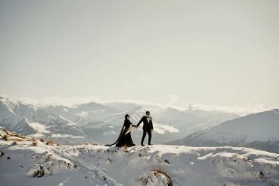 Kyoto Tokyo Japan Elopement Wedding Photographer, Planner & Videographer | Ayaka Morita's Portfolio showcases a stunning image of a bride and groom standing on top of a snow covered mountain.