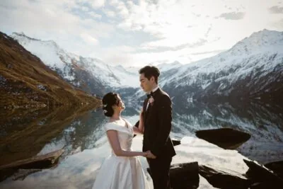 Kyoto Tokyo Japan Elopement Wedding Photographer, Planner & Videographer | Ayaka Morita's portfolio featuring a bride and groom standing in front of a lake with mountains in the background.