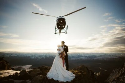 Kyoto Tokyo Japan Elopement Wedding Photographer, Planner & Videographer | A bride and groom standing on top of a mountain with a helicopter in the background, captured beautifully by Ayaka Morita.