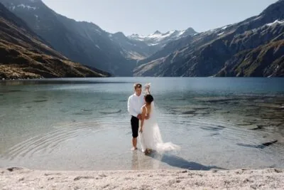 Kyoto Tokyo Japan Elopement Wedding Photographer, Planner & Videographer | Portfolio: A stunning image featuring Ayaka Morita capturing a bride and groom standing in the shallow water of a lake in New Zealand.