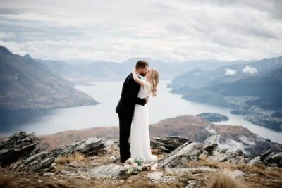 Kyoto Tokyo Japan Elopement Wedding Photographer, Planner & Videographer | Ayaka Morita captures a picturesque moment as a bride and groom share an intimate kiss on top of a mountain overlooking Lake Wanaka. Their love is beautifully captured in Ayaka Morita's