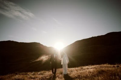 Kyoto Tokyo Japan Elopement Wedding Photographer, Planner & Videographer | Ayaka Morita's portfolio showcases a beautiful image of a bride and groom standing in a field with the sun setting behind them.