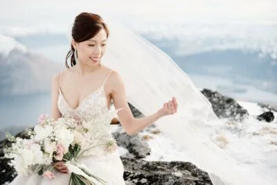 Kyoto Tokyo Japan Elopement Wedding Photographer, Planner & Videographer | Ayaka Morita's portfolio includes a stunning image of a bride sitting atop a snowy mountain, clutching her wedding bouquet.
