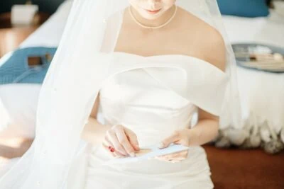 Kyoto Tokyo Japan Elopement Wedding Photographer, Planner & Videographer | Ayaka Morita, a bride in a white wedding dress, showcasing her portfolio with a wedding card in hand.