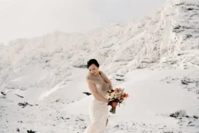 Kyoto Tokyo Japan Elopement Wedding Photographer, Planner & Videographer | Ayaka Morita's portfolio showcases a stunning image of a bride standing in front of a snow covered mountain.