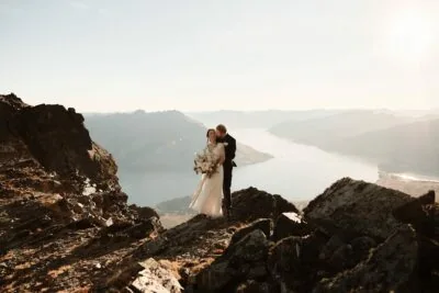 Kyoto Tokyo Japan Elopement Wedding Photographer, Planner & Videographer | Ayaka Morita, a talented photographer, captured an enchanting moment of a bride and groom standing on top of a cliff overlooking a serene lake. This captivating image perfectly showcases Ayaka Morita's