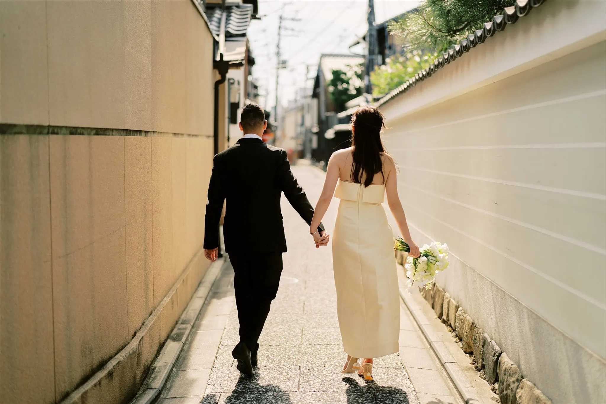 Kyoto Tokyo Japan Elopement Wedding Photographer, Planner & Videographer | A bride and groom elegantly strolling down a narrow alleyway in Japan during their elopement ceremony.