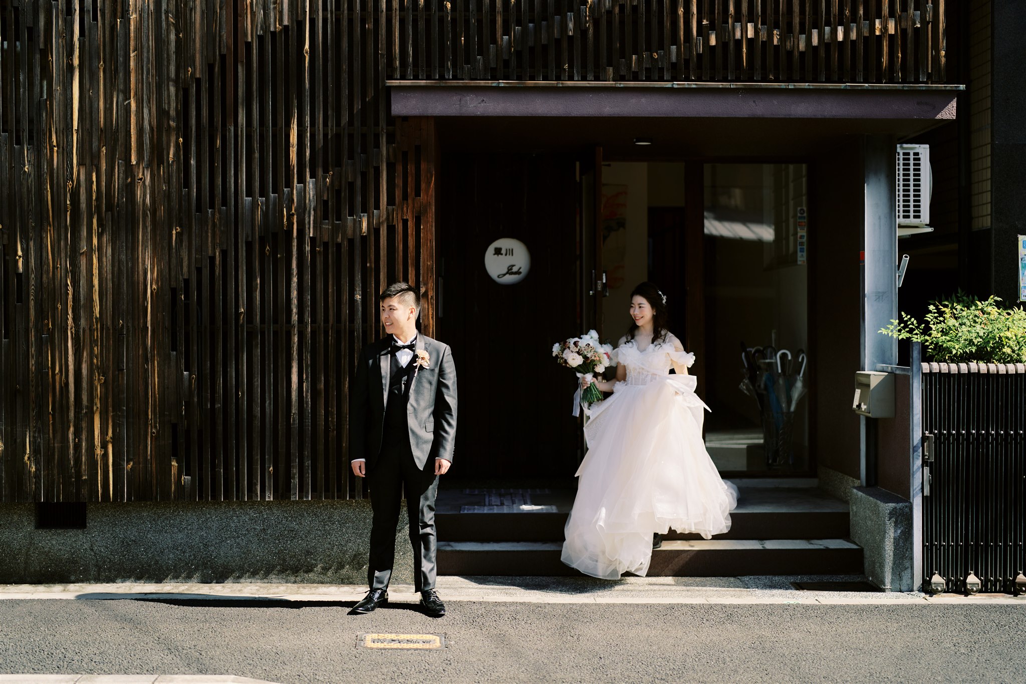 Kyoto Tokyo Japan Elopement Wedding Photographer, Planner & Videographer | A Japan elopement photographer captures a bride and groom standing in front of a building.