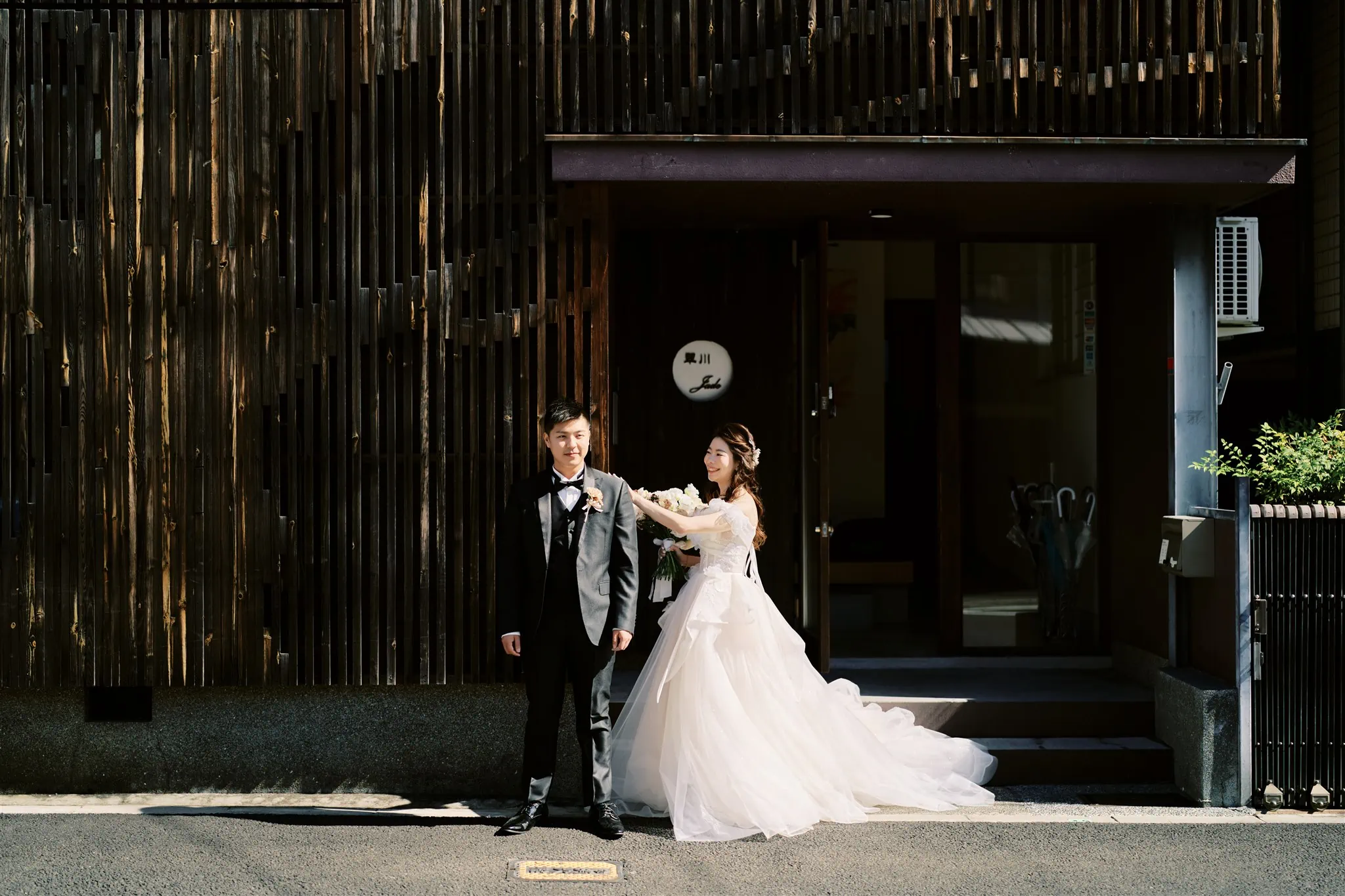 Kyoto Tokyo Japan Elopement Wedding Photographer, Planner & Videographer | A Japan elopement photographer captures the momentous occasion of a bride and groom standing in front of a wooden building.