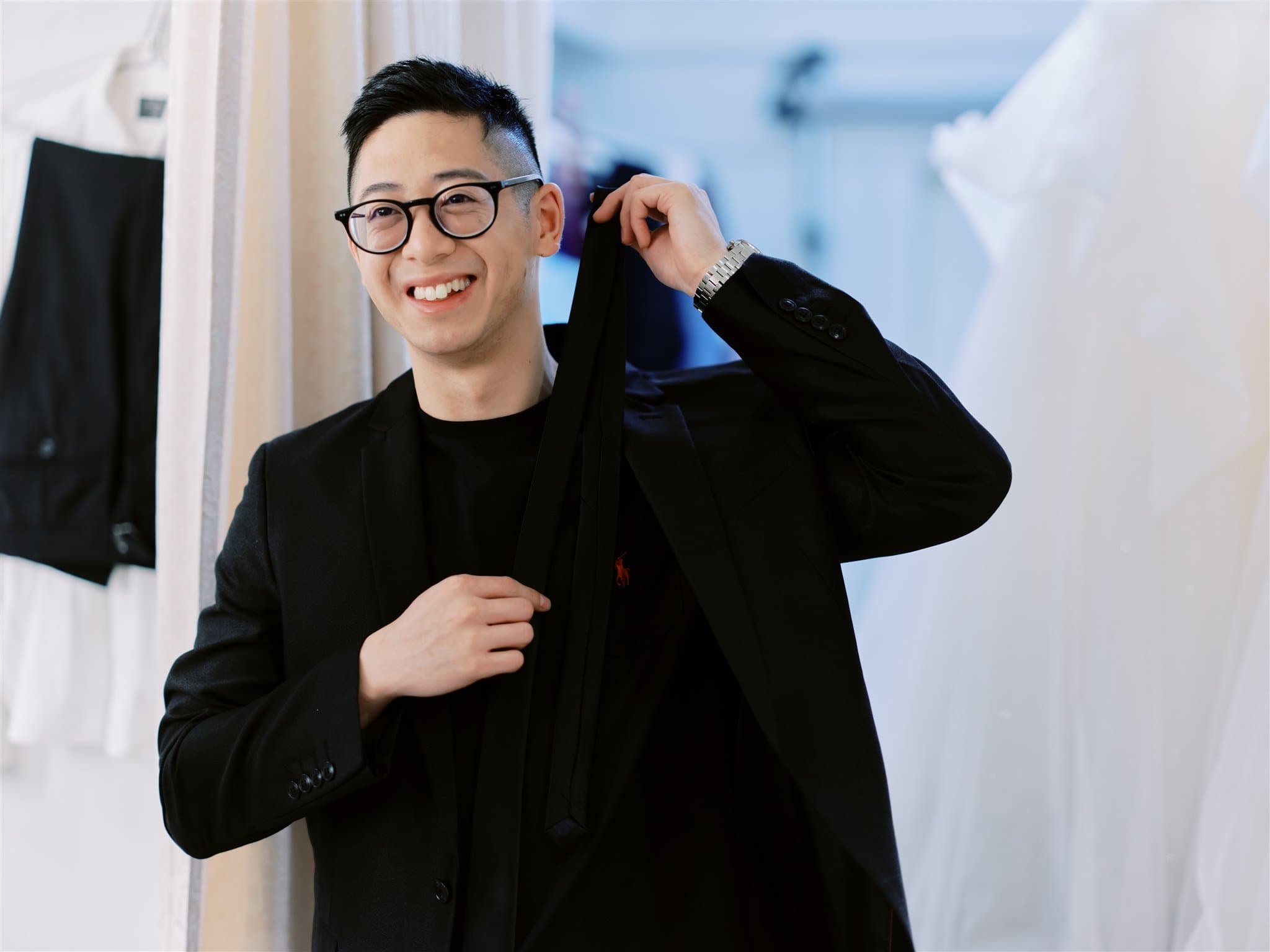 Kyoto Tokyo Japan Elopement Wedding Photographer, Planner & Videographer | A man wearing glasses and a suit in a dress shop searching for the perfect attire for his Japan elopement.