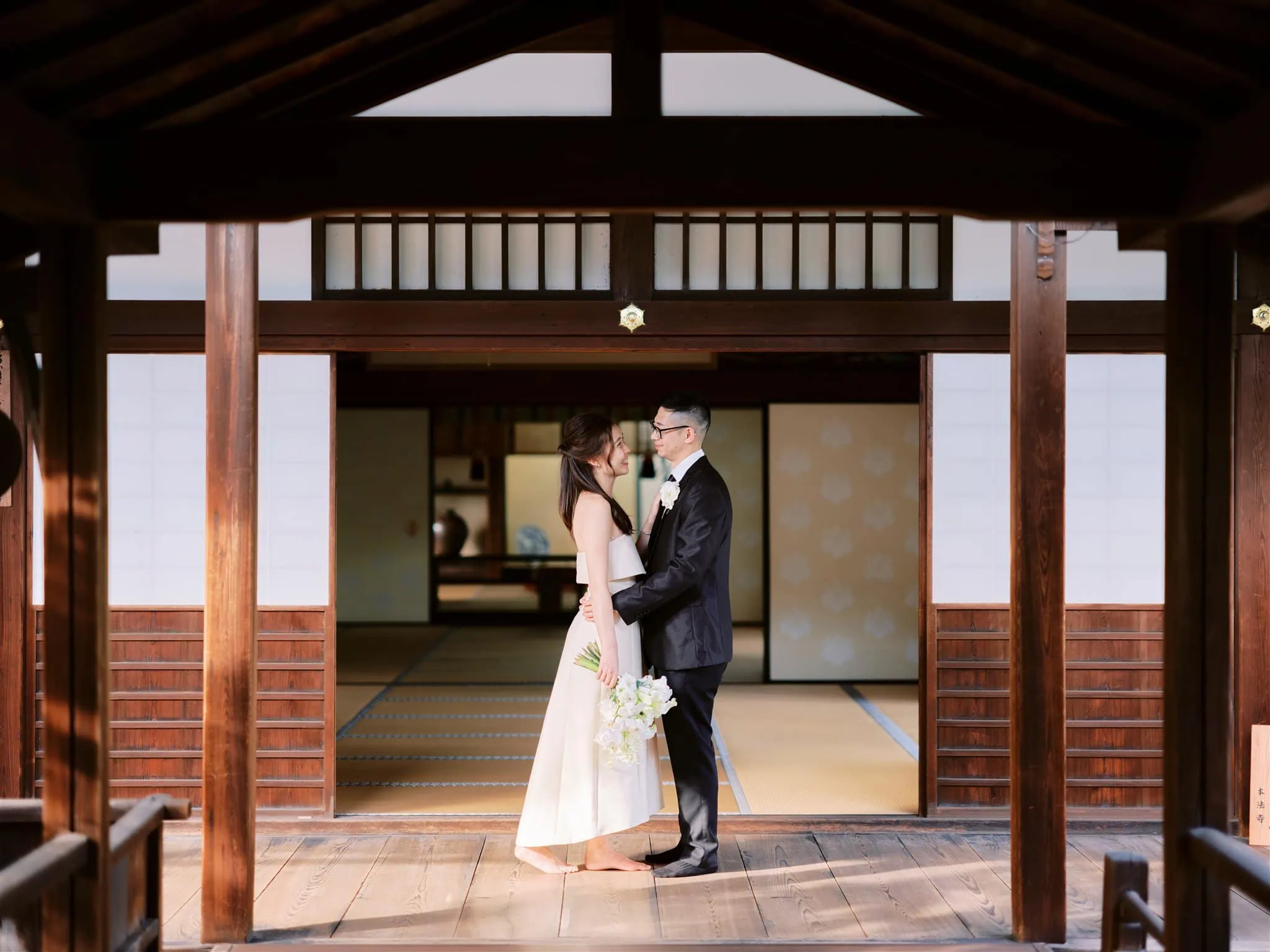 Kyoto Tokyo Japan Elopement Wedding Photographer, Planner & Videographer | A Japan elopement with a bride and groom standing in front of a wooden structure.