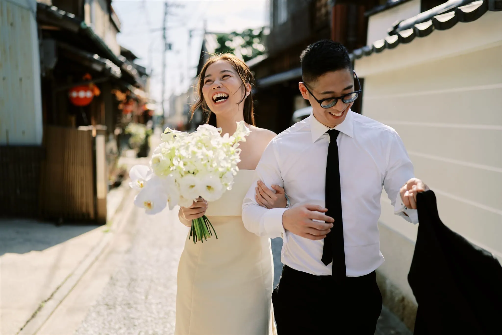 Kyoto Tokyo Japan Elopement Wedding Photographer, Planner & Videographer | A joyful bride and groom laughing as they elope down a narrow street in Japan.