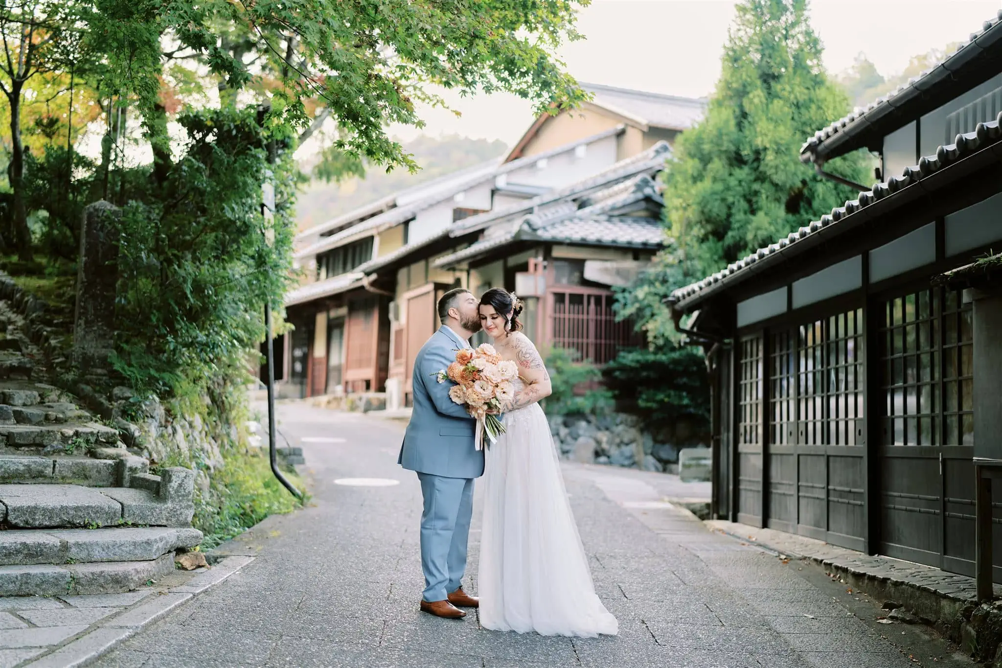 Kyoto Tokyo Japan Elopement Wedding Photographer, Planner & Videographer | A photographer captures a bride and groom's romantic kiss during their Japan elopement in front of a traditional Japanese house.