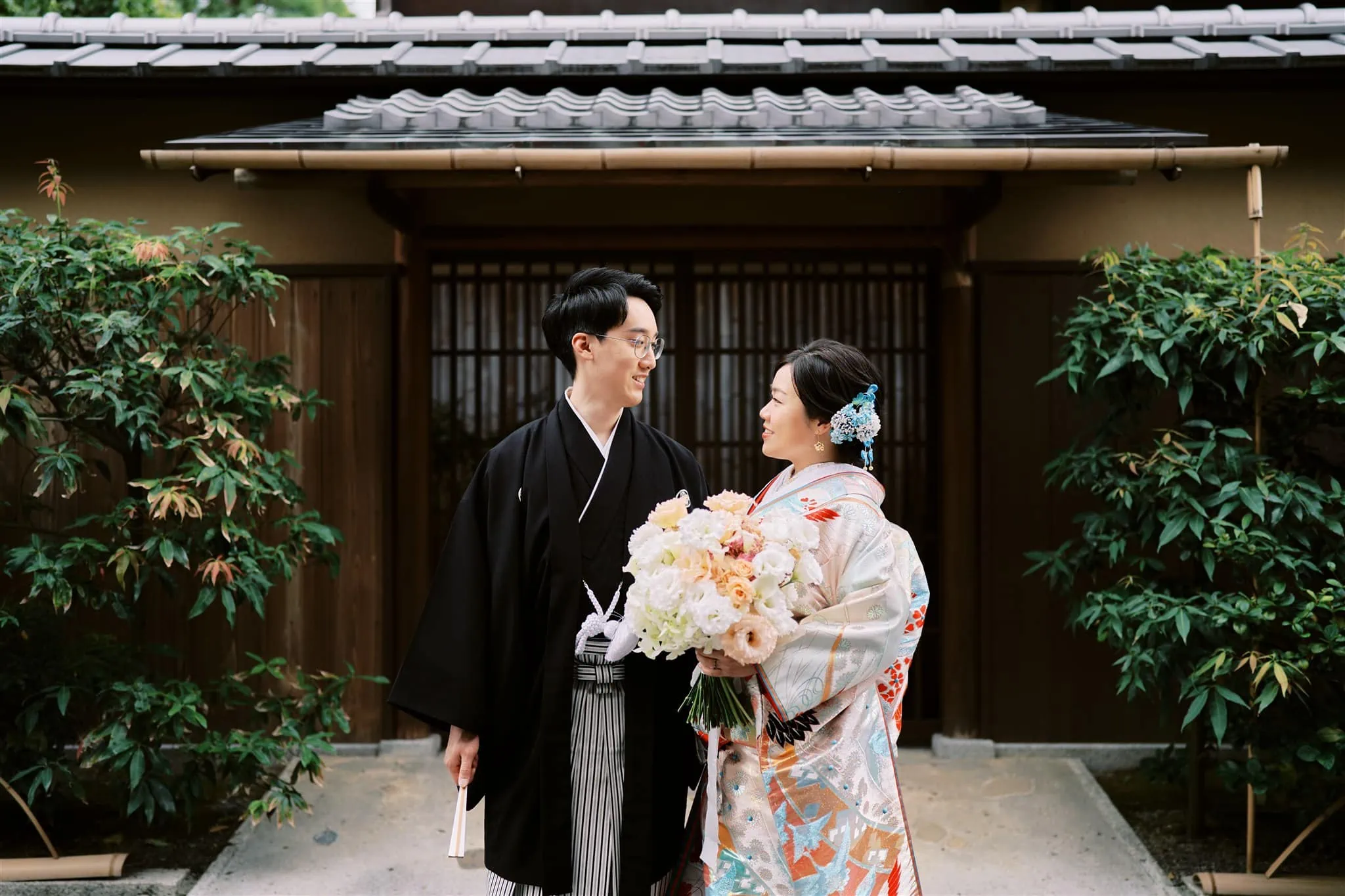 Kyoto Tokyo Japan Elopement Wedding Photographer, Planner & Videographer | An elopement photographer captures a bride and groom in traditional Japanese kimono standing in front of a house.