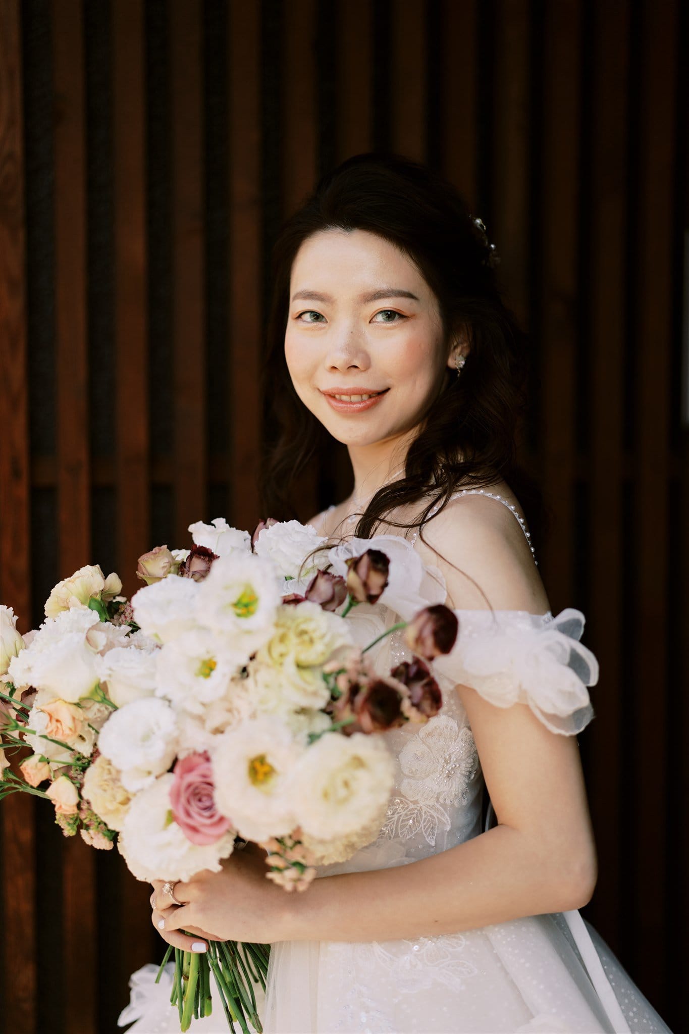 Kyoto Tokyo Japan Elopement Wedding Photographer, Planner & Videographer | A Japan elopement photographer captures a bride holding a bouquet in front of a wooden wall.