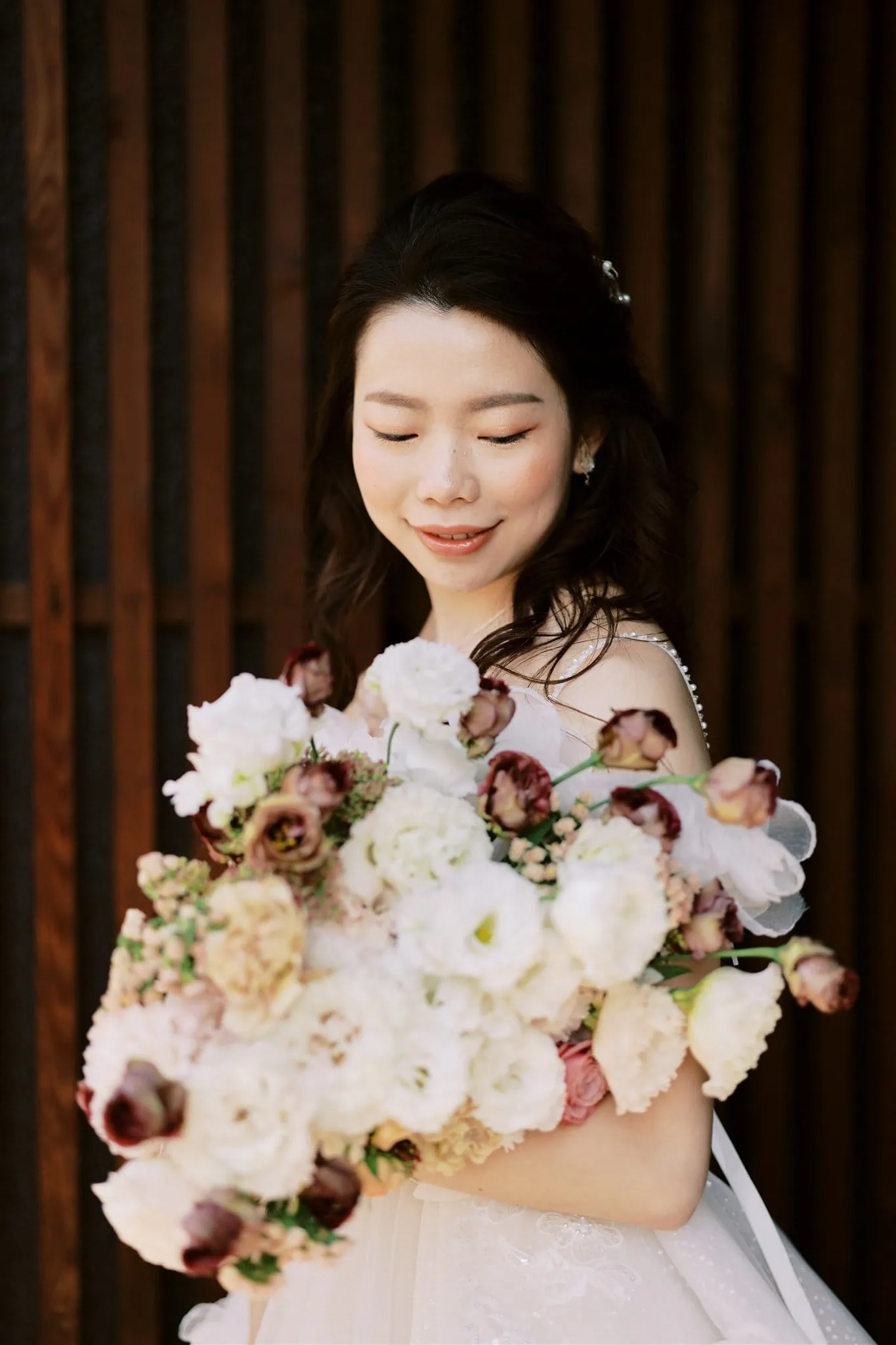 Kyoto Tokyo Japan Elopement Wedding Photographer, Planner & Videographer | A Japan elopement photographer captures a bride holding a bouquet of flowers in front of a wooden wall.