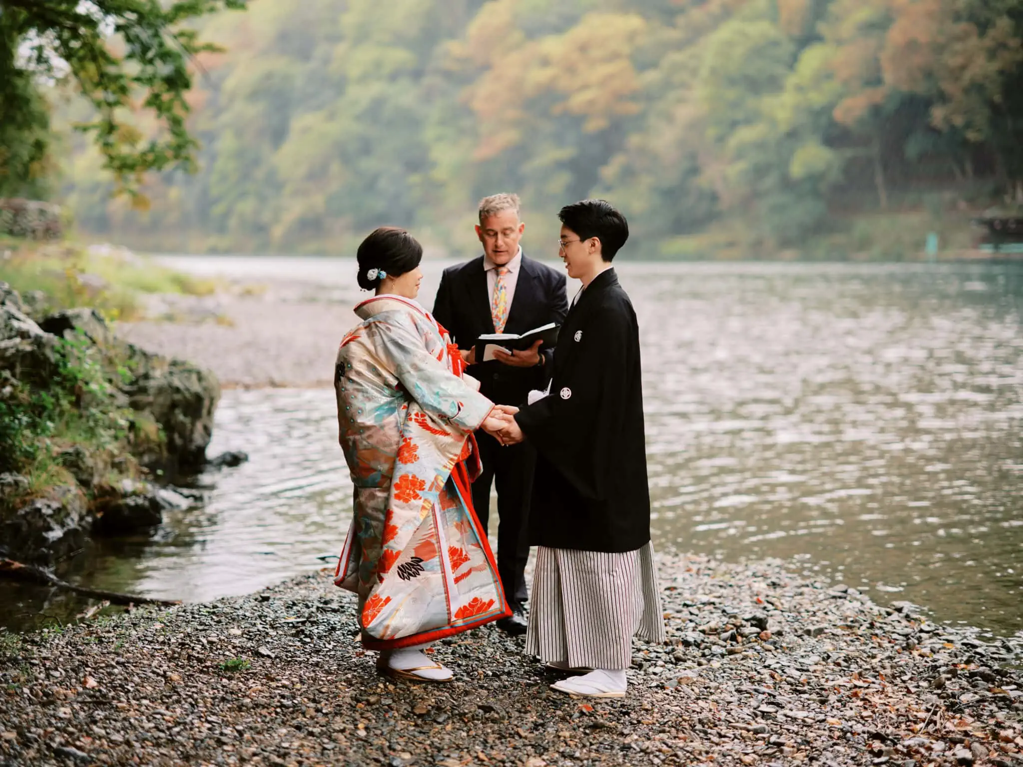 Japan Elopement Wedding Photographer, Planner & Videographer | A couple in kimono enjoying Kyoto Wedding Elopement Package by standing next to a river in Arashiyama