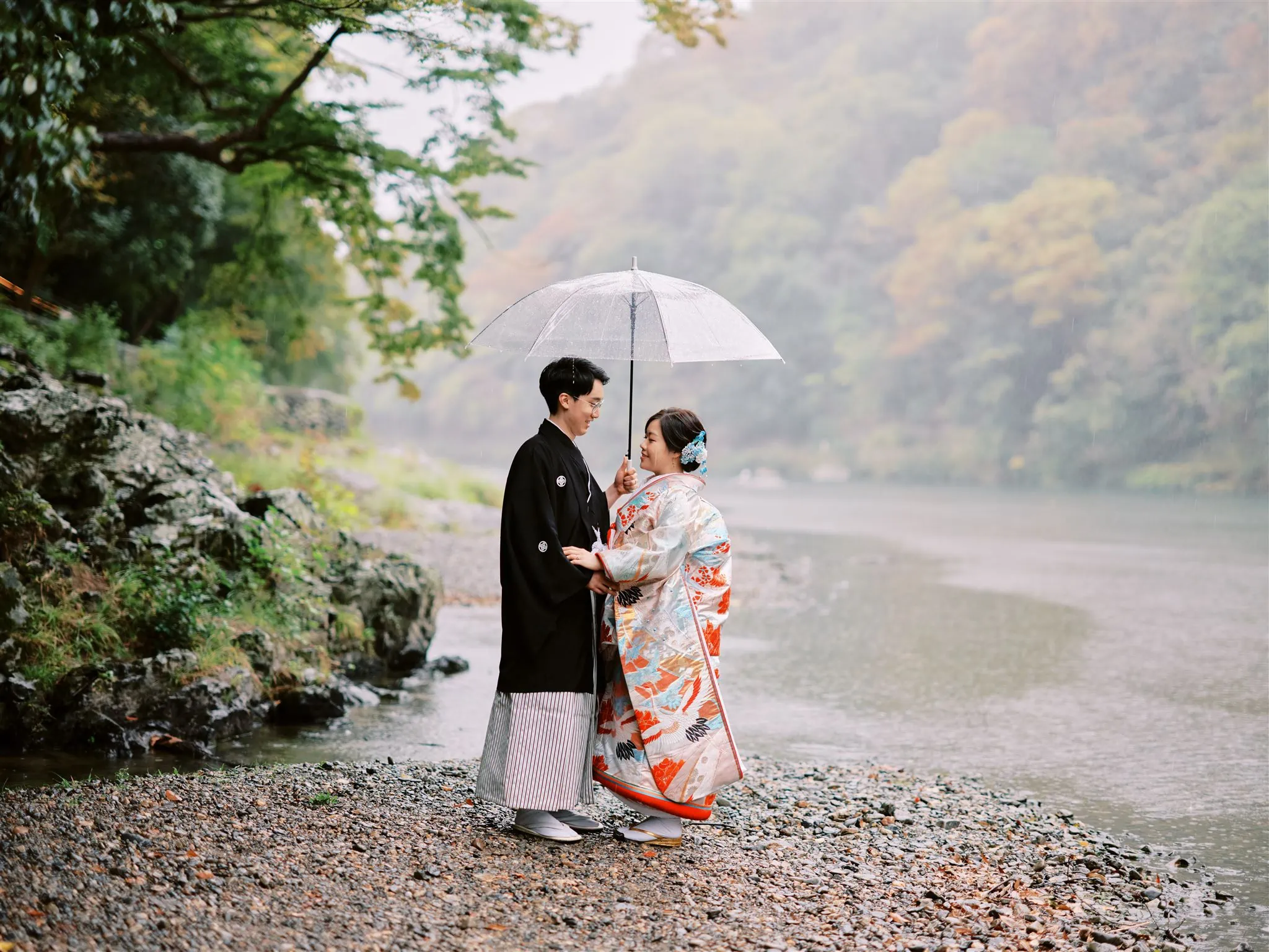 Kyoto Tokyo Japan Elopement Wedding Photographer, Planner & Videographer | An elopement photographer captures a japanese couple standing by a river with an umbrella.