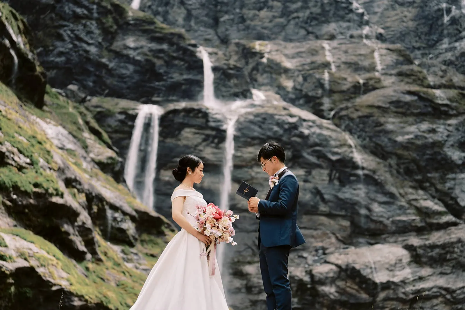 Kyoto Tokyo Japan Elopement Wedding Photographer, Planner & Videographer | A couple exchanging vows in front of a waterfall, captured by Yuri, a renowned Japan Wedding Photographer.