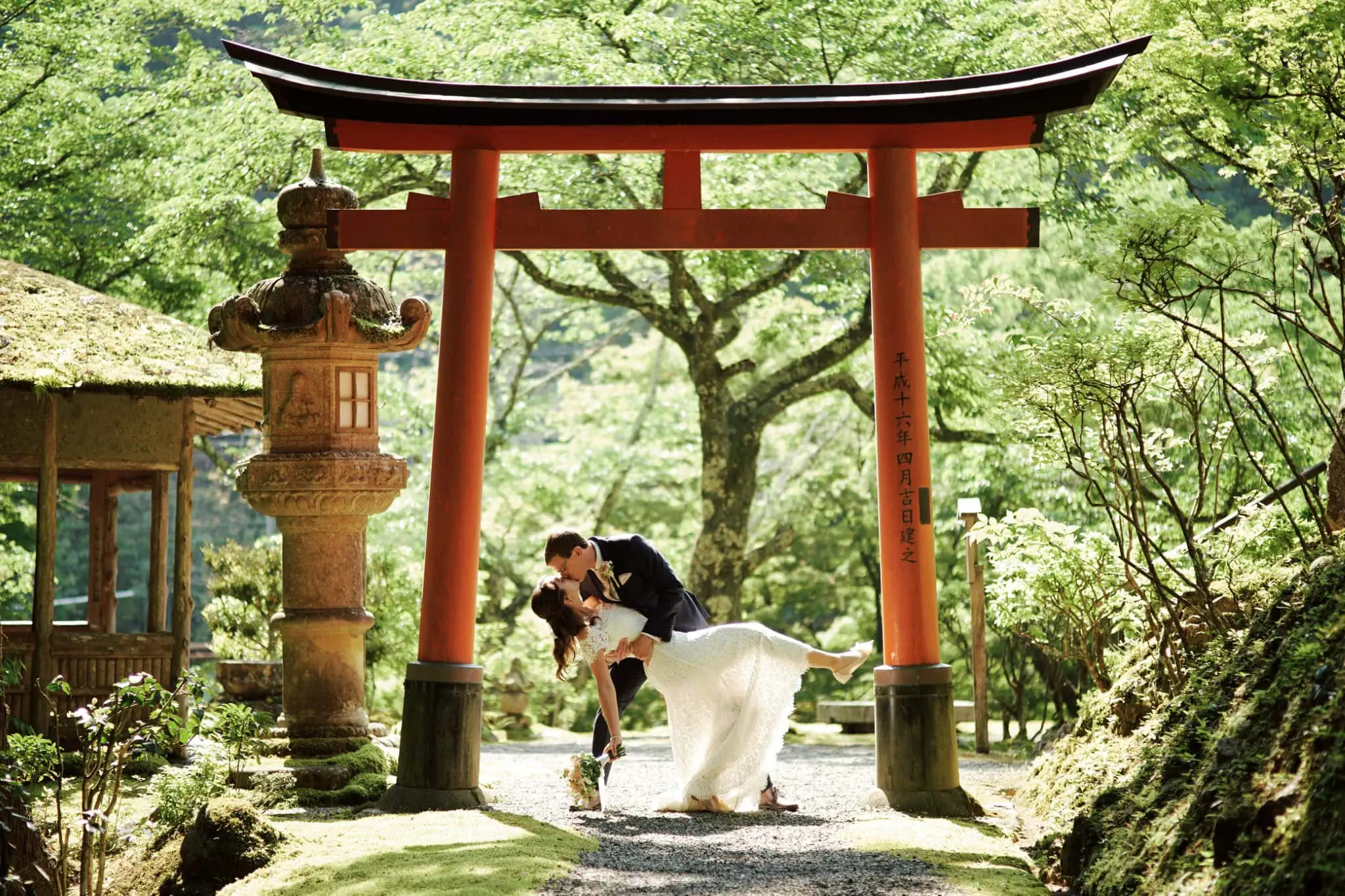 Bride and groom under torii gate in a Kyoto garden
